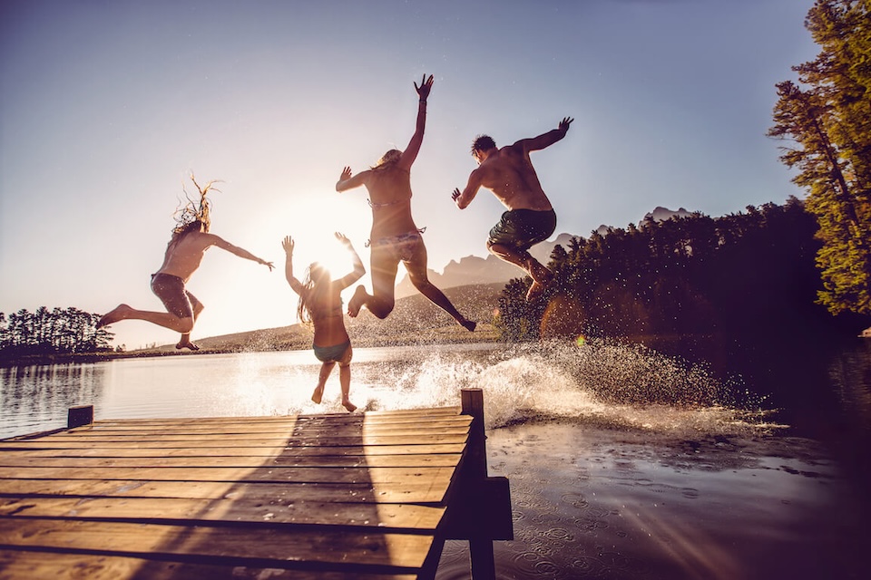 Jeunes adultes sautant dans un lac sur le bord d'un quai